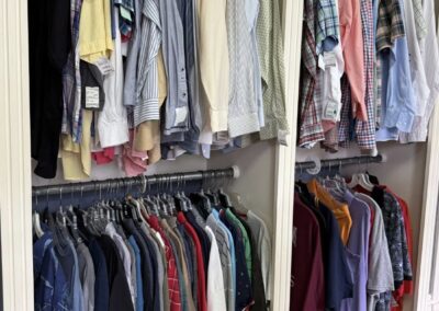 A well-organized closet features neatly hung shirts and t-shirts in various colors and patterns on two-tiered racks, showcasing a tidy clothing collection.